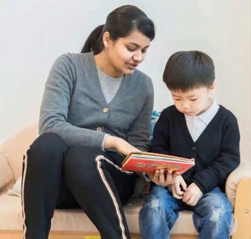 A Montessori guide reading a picture book alongside a child